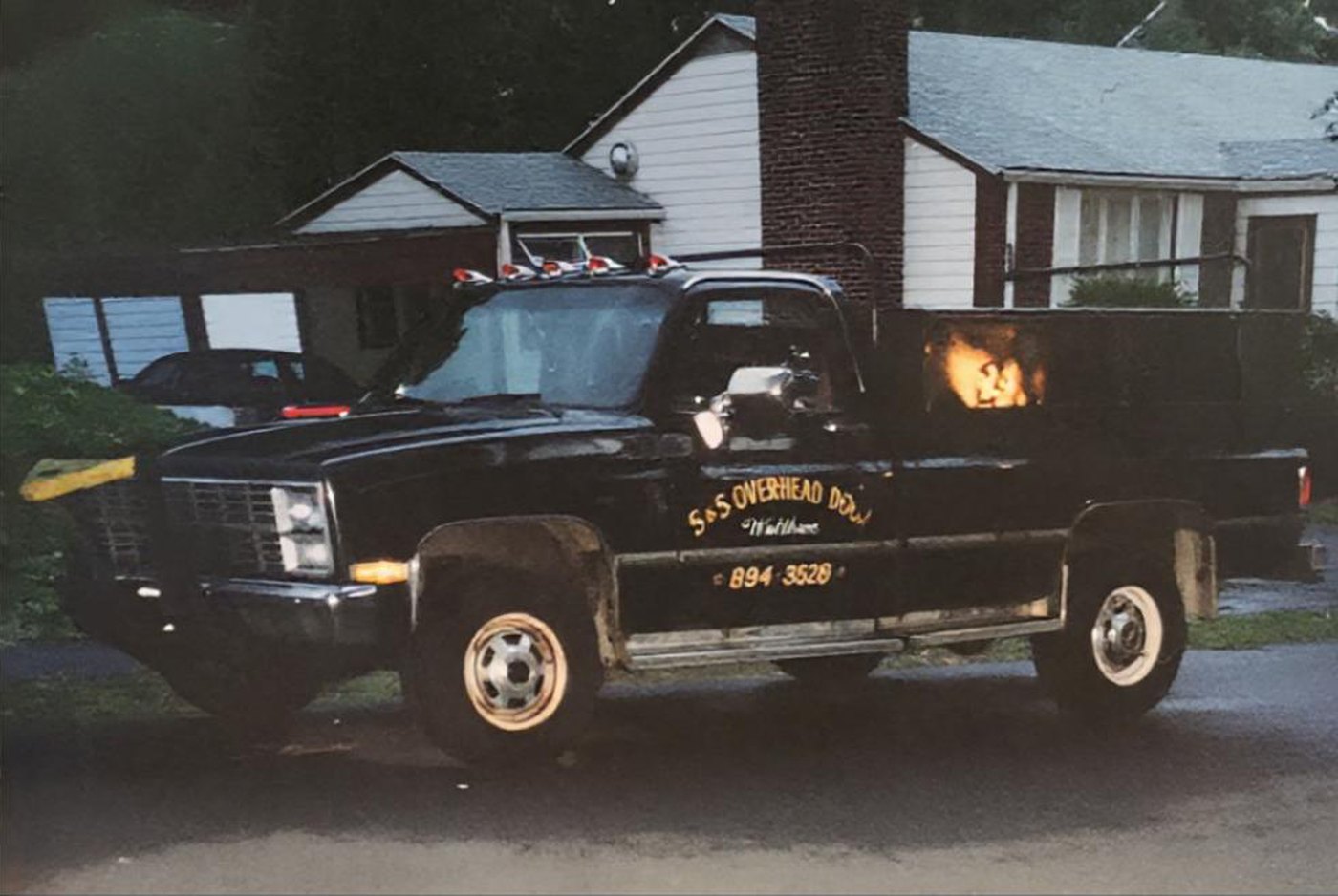 The black S and S Overhead Door pickup with gold hand lettering, parked in a Waltham driveway