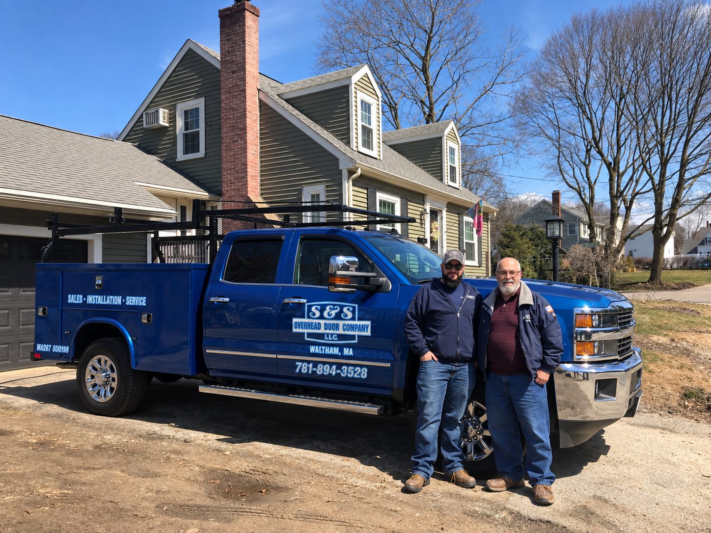 Justin and Gary standing beside the blue S and S Overhead Door service truck in a driveway