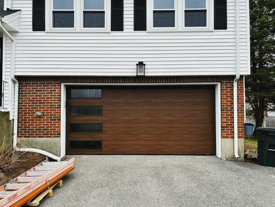 Wood look sectional garage door on a brick and clapboard house