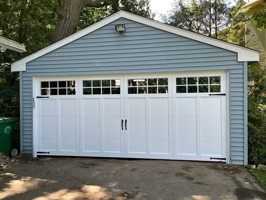 White carriage door on a gray garage among autumn trees
